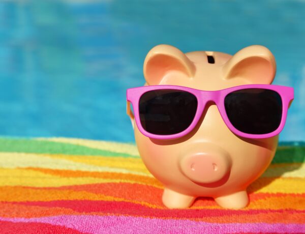Tirelire d'été avec lunettes de soleil devant une piscine