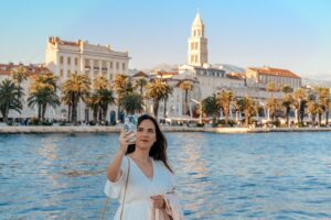 Vue de face d'une femme prenant un selfie devant la ville de Split en Croatie